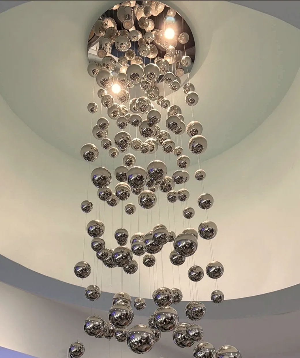 A cascade of silver spheres suspended from a circular ceiling recess at Radiant Sun Wellness.
