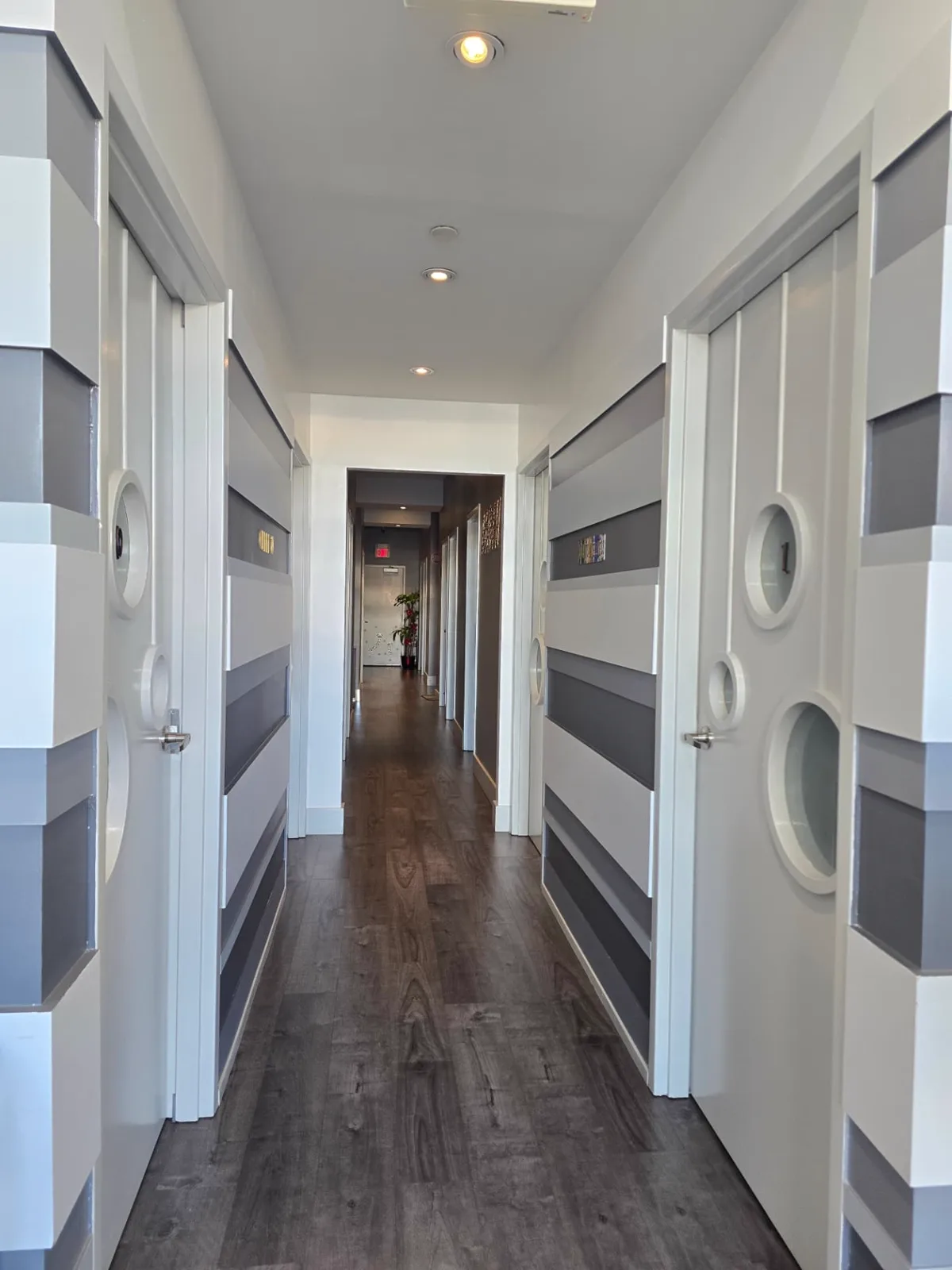 A quiet hallway lined with numbered treatment room doors and striped grey walls.