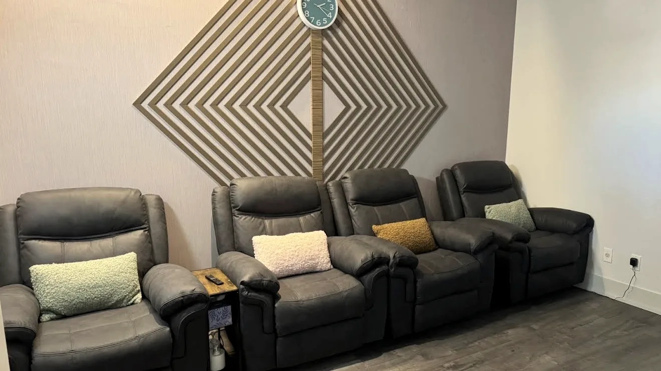 The relaxation lounge at Radiant Sun Wellness, with reclining chairs beneath a geometric wood feature wall.
