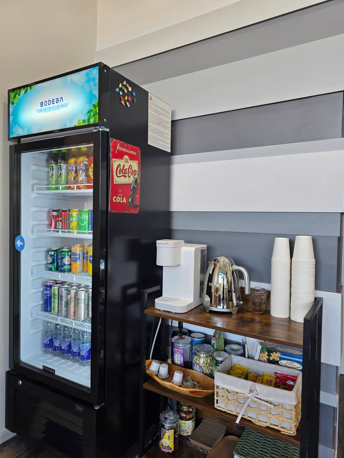 A refreshment station with a drinks cooler, kettle, cups and jars of tea at Radiant Sun Wellness.